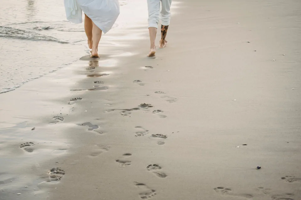 A couple walking barefoot along a sandy beach; illustrative lifestyle photograph